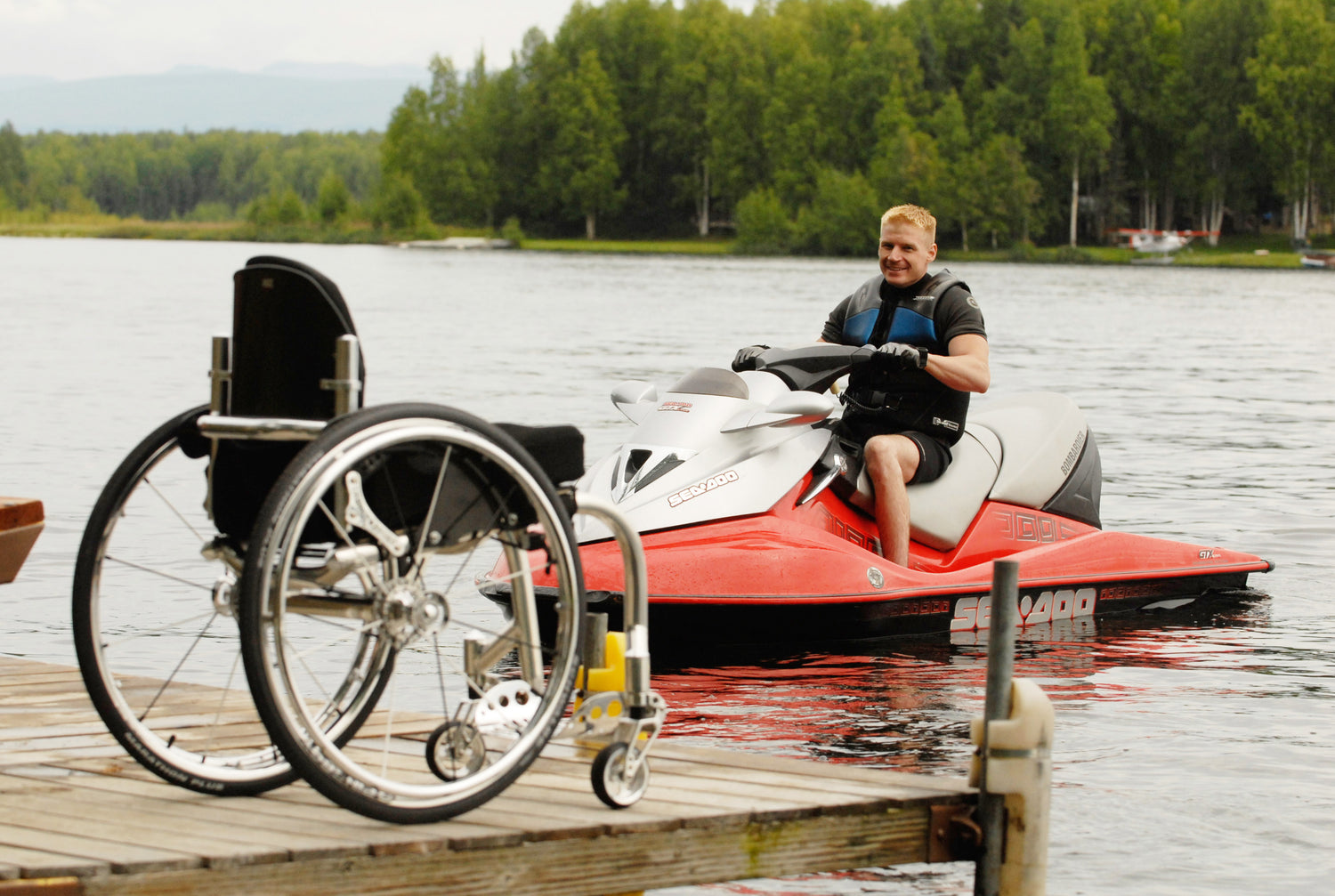 Man riding a Jet Ski with his wheelchair on a wooden dock